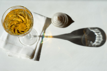Light background with a glass of wine and lace shadow on the table.
