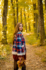 Autumn sale. Beautiful happy smiling girl with long hair wearing stylish jacket posing in autumn day. Autumn portrait smiling woman holds yellow maple leaves in park.