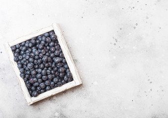 Fresh raw organic blueberries in vintage wooden box on stone kitchen background. Space for text. Top view