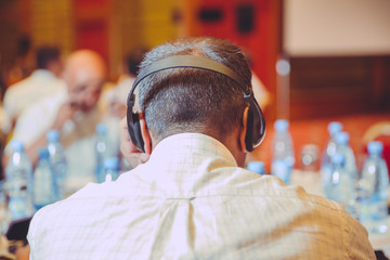 Unrecognizable people using in ear headphones for translation during event