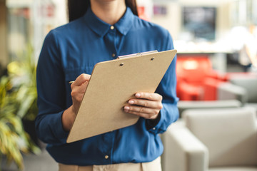 Businesswoman writing on document at tablet. Close up of map-case in hands of lady. Cafe on blurred background
