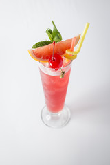 Alcohol fresh grapefruit cocktail with cherry and mint on white background