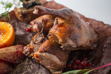 Grilled duck with apple, red berries, orange and red pear on wooden board