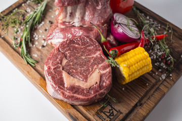 Raw stenderloin with lamb, corn, onion, pepper chili, green and tomato on wooden board