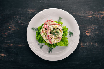 Vegetable salad with mayonnaise. On the old wooden background. Free space for text. Top view.