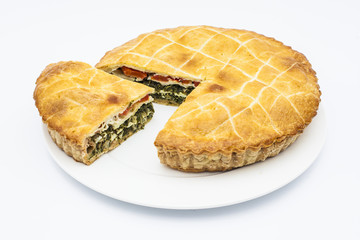 Spinach pie with tomatoes on white plate