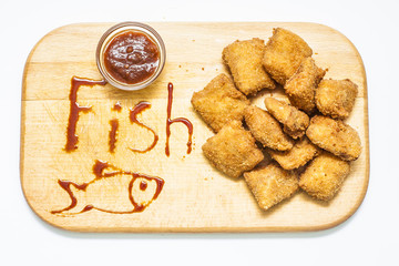 Fish nuggets with bbq sauce on wooden board