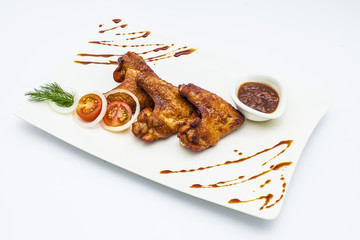 Honey chicken wings with onion, tomatoes, green and bbq sauce on white plate