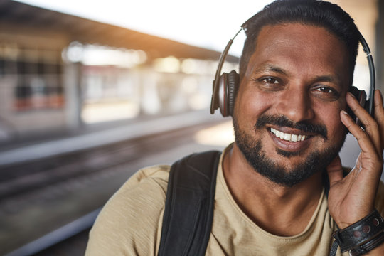 Close up of a bearded positive hindu man wearing headphones while expressing joy