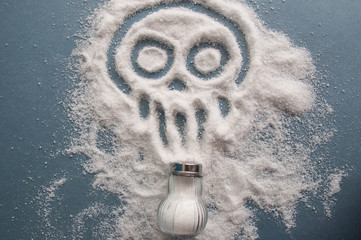 A pile of salt from salt shaker, skull, concept excessive salt intake and white death 