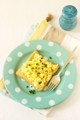 Simple classic breakfast of bread toast and scrambled eggs with parsley.