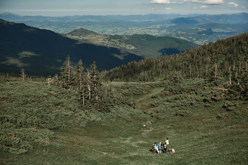 Top view of five tourists travelling in mountains with knapsacks. They having break in descent and...