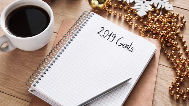 2019 goals list in notebook, cup of coffee on wooden desk