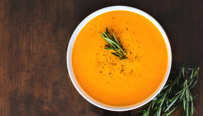Pumpkin and carrot  Cream soup on  wooden background. Autumn cream-soup in country style. Top view. Copy space.
