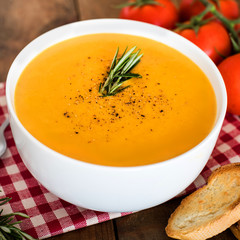 Squash Soup with Rosemary on rustic wooden table.  Autumn Pumpkin cream-soup in a white bowl  with croutons. Top view.