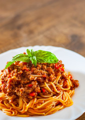Traditional pasta spaghetti bolognese in white plate on wooden table background
