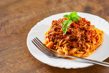 Traditional pasta spaghetti bolognese in white plate on wooden table background