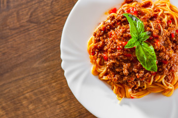 Traditional pasta spaghetti bolognese in white plate on wooden table background
