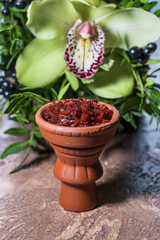 Hookah in a clay bowl for Smoking hookah on the background of greenery and orchids
