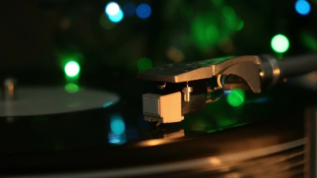 Close up of vinyl turntable record player rotating disc. Multicolored light.