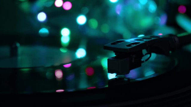 Vinyl disc running on turntable record player. Neon noir cold light background.