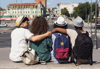 Young tourists resting, looking around sitting together