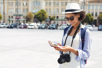 African-american tourist reading guide book in city