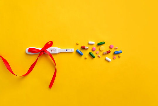 Pregnancy Test, Pills And Vitamins On A Yellow Background.