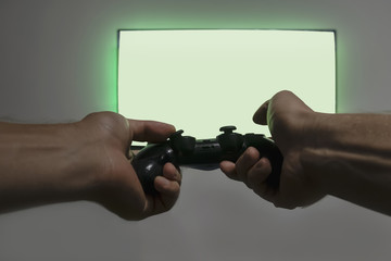 Man hold gamepad in hands in front of blank tv screen mock up, playing game. Clean monitor mockup with one gamer person © domarevatanya