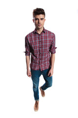 young man wearing jeans and shirt with plaids walking