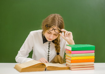 Thoughtful teen girl near a school board read book