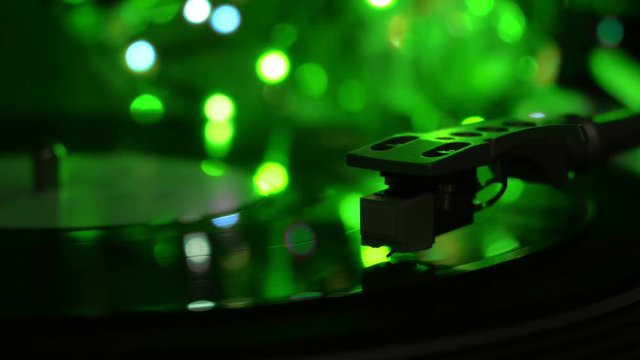 Turntable record player spinning vinyl disc. Toxic green light background.
