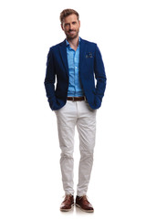 Fototapeta premium happy young smart casual man standing with hands in pockets