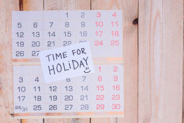 Time For Holiday written on paper note on a wall calendar with wooden background and copy space