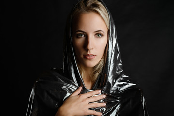 Portrait of beautiful woman in cape on dark background.