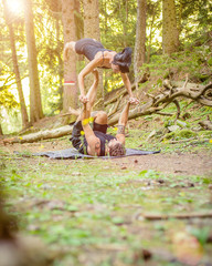 Giovane coppia pratica acroyoga in un bosco naturale