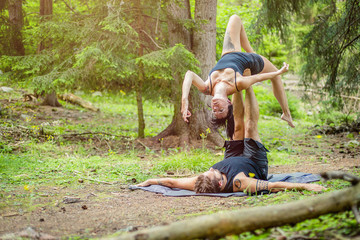 Giovane coppia pratica acroyoga in un bosco naturale