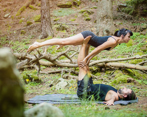 Giovane coppia pratica acroyoga in un bosco naturale