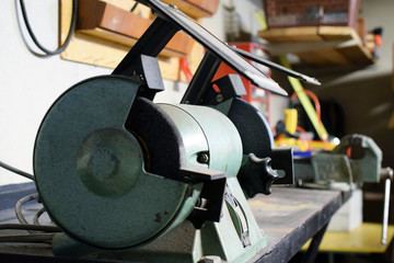 Metal workshop close up. Bench grinder on foreground, vise on background. Shollow depth of field.