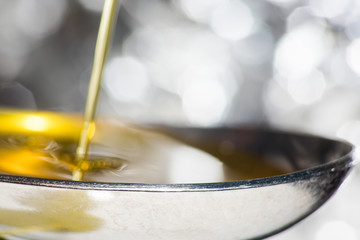 Oil is poured on a spoon on the background of light bokeh