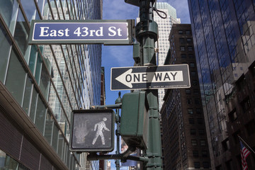 One Way road sign, pedestrian traffic lights with white light on East 43rd Street in New York City