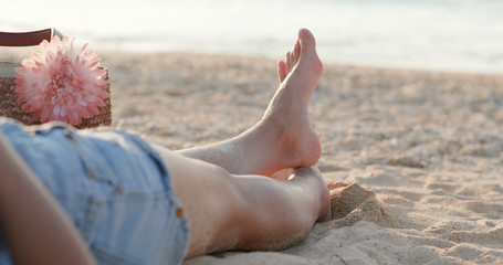 Woman lying on the beach under sunset