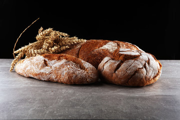 Different kinds of bread and bread rolls on board from above. Kitchen or bakery