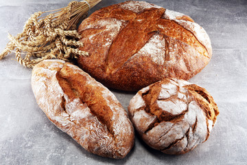 Different kinds of bread and bread rolls on board from above. Kitchen or bakery