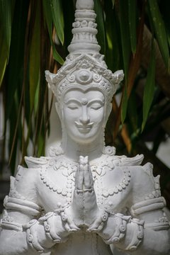 white buddha sculpture in temple with praying hands