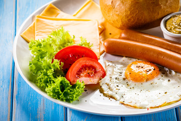 English breakfast - fried egg,sausages,bun and vegetables