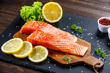 Fresh raw salmon fish served on black stone on wooden table