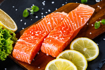 Fresh raw salmon fish served on black stone on wooden table