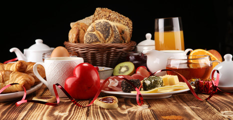 breakfast on table with bread buns, croissants, coffe and juice on valentines day.