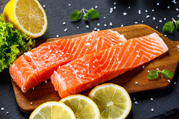 Fresh raw salmon fish served on black stone on wooden table